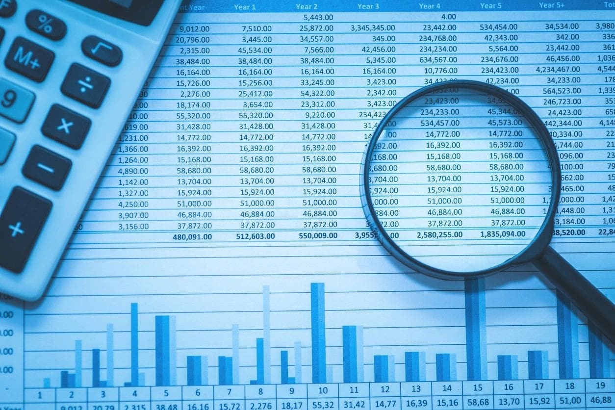 A magnifying glass sitting on top of a spreadsheet.