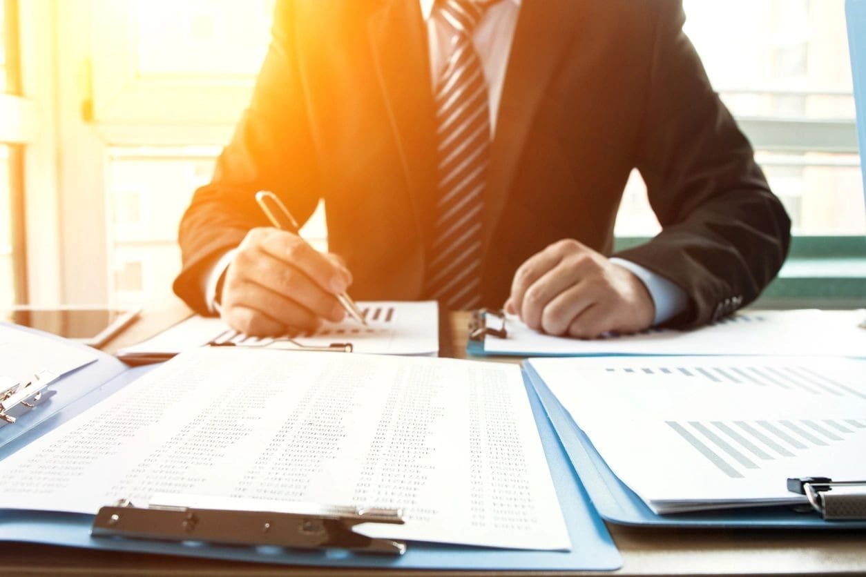 A man in a suit and tie writing on paper.