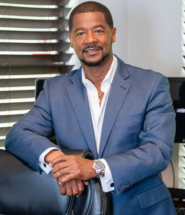 A man in a suit and tie standing next to a window.