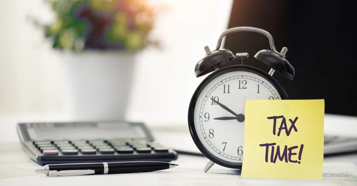 A clock sitting on top of a desk next to a keyboard.