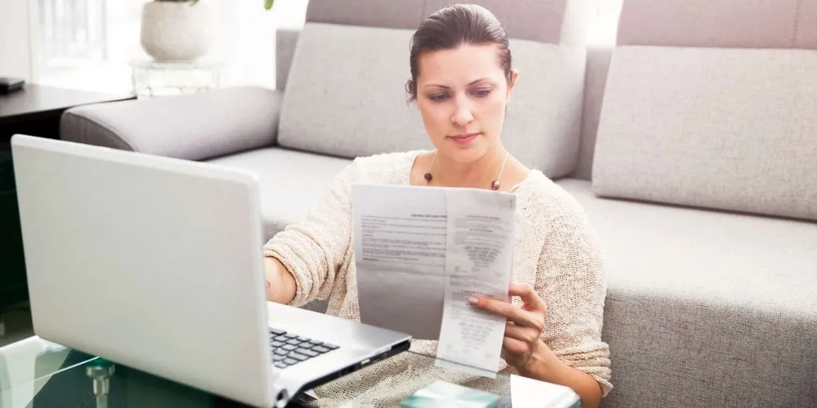 A woman sitting on the couch looking at papers.