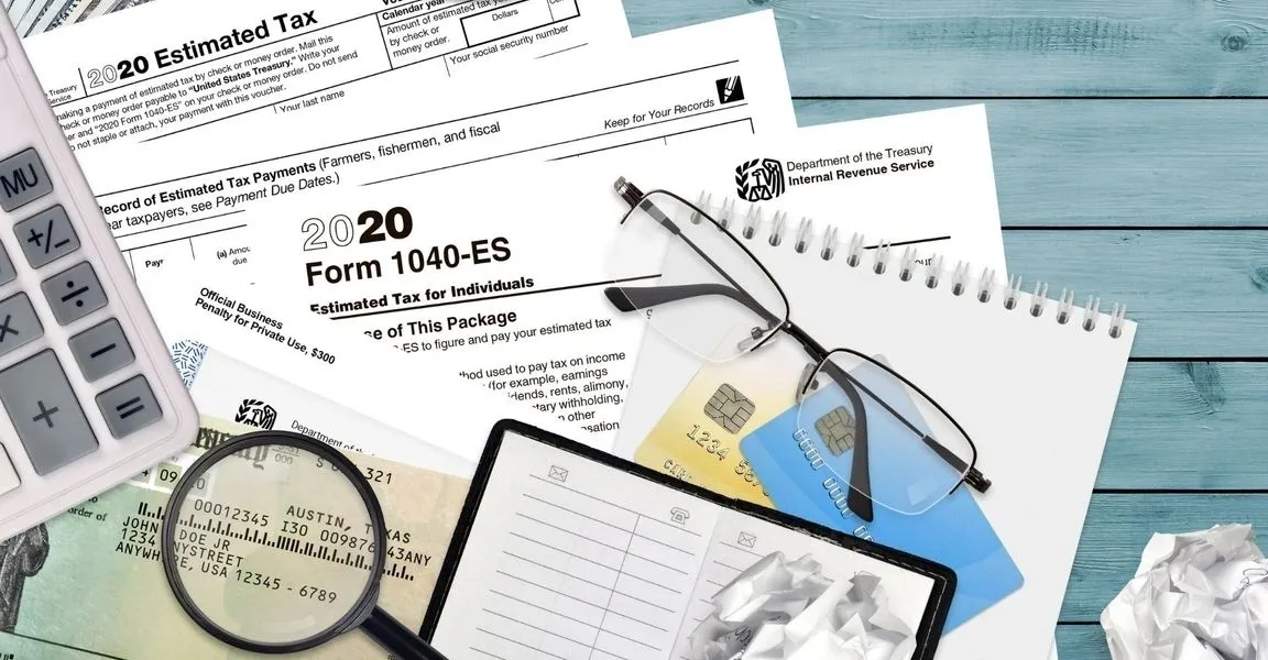 A table with tax forms, glasses and papers.