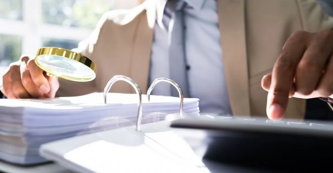 A person sitting at a table with papers and a phone.