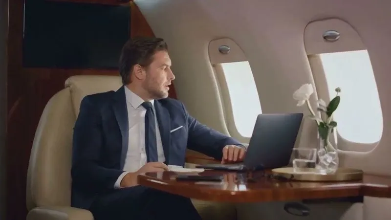 A man in a suit and tie sitting at a table with a laptop.