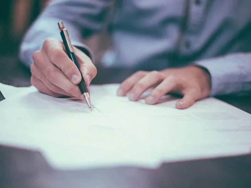 A person writing on paper with a pen.