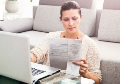 A woman sitting on the couch looking at papers.